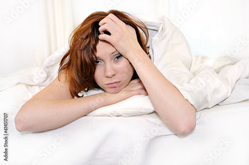 red hair woman on bed waking up with hangover and headache