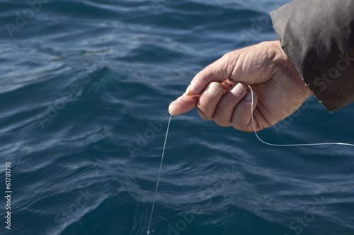 Man with fishing line in his hand catching fish from the boat