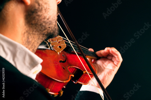 Violinist playing in black background.