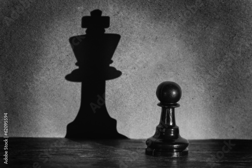 Chess pawn standing in a spotlight that make a shadow actistic