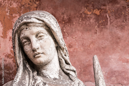 portrait of a weathered sculpture of maria with red background