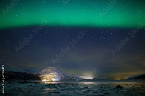 Green aurora borealis over a frozen fjord