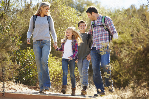 Family Hiking In Countryside Wearing Backpacks