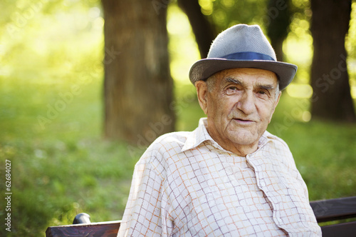 Senior man relaxing outdoors on a park early in the morning.