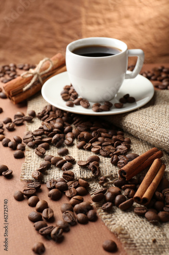 Coffee beans and cup of coffee on table on brown background