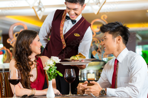 Chinese waiter serving dinner in elegant restaurant or Hotel