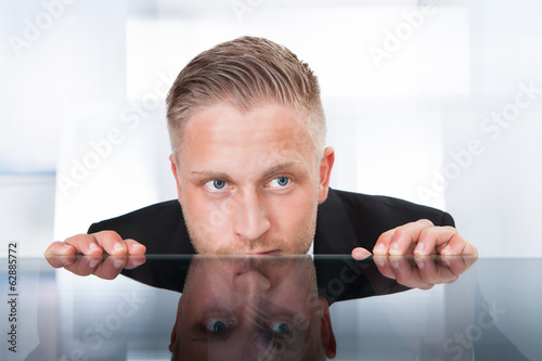 Businessman peering furtively over the top of his desk