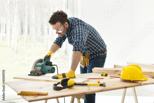 Carpenter cutting plank by circular saw