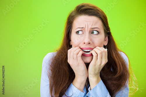 Anxiety. Scared woman biting fingernails, green background 