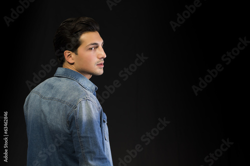 Young man w denim shirt seen from the back, looking to a side