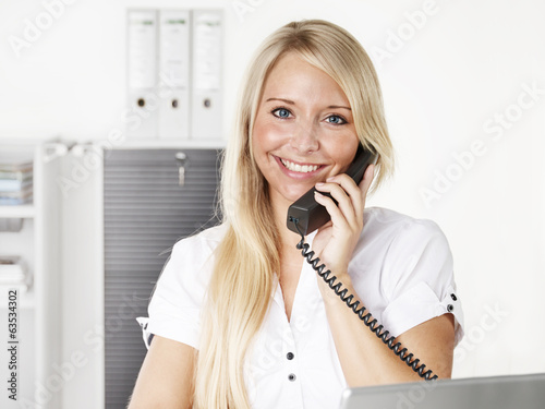 Female office assistant has a call at the office