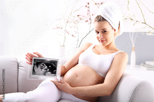 Kobieta w ciąży pokazuje usg dziecka
