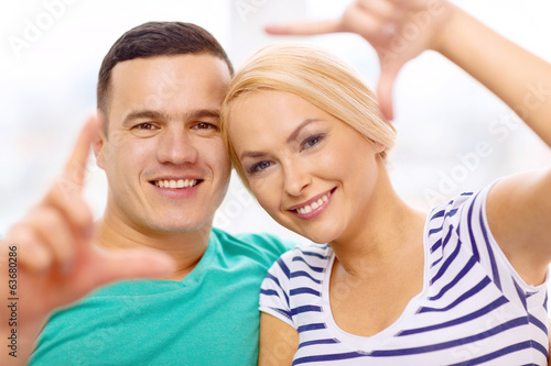 smiling happy couple making frame gesture at home
