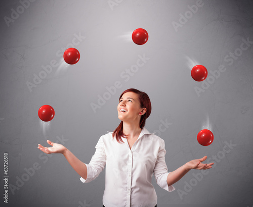 young girl standing and juggling with red balls