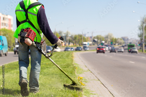 Road landscaper cutting grass along the street