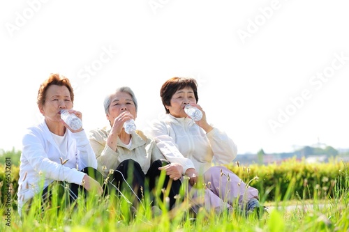 仲良くペットボトルの水を飲んで休憩する３人の高齢者女性