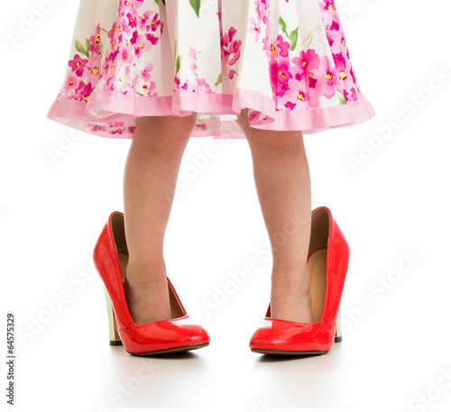Kid girl in big mommy shoes isolated on white