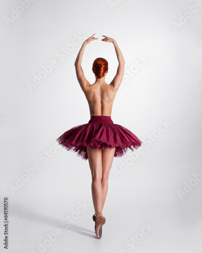 Young naked redhead female ballet dancer in a studio