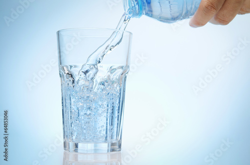 pure water is emptied into a glass of water from bottle