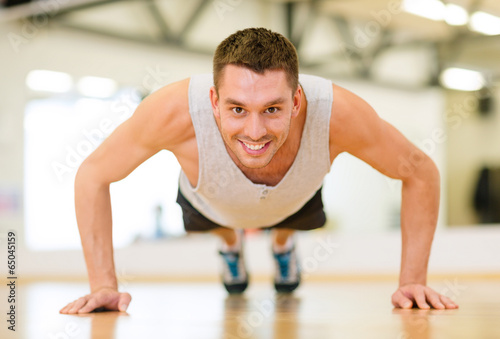 smiling man doing push-ups in the gym