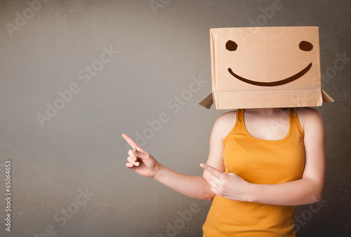 Young lady gesturing with a cardboard box on her head with smile