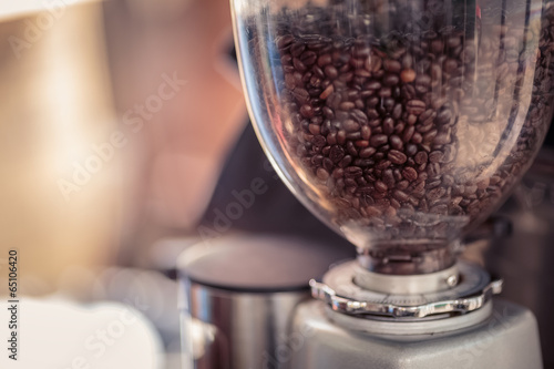 Coffee grinder and Barista prepares espresso in coffee shop