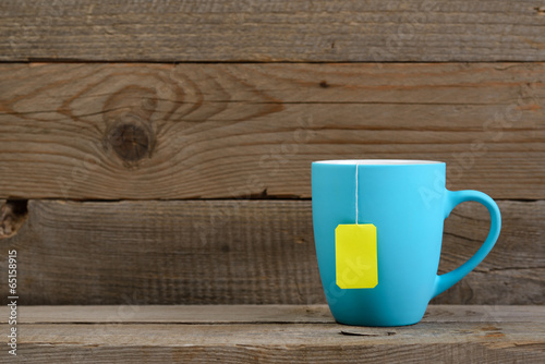 Cup of tea with tea bag on old wooden background