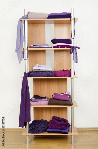 Tidy wardrobe with purple clothes nicely arranged on a shelf.