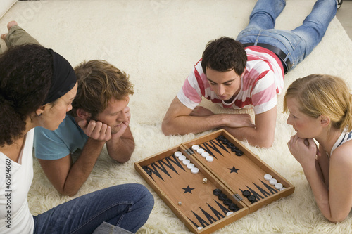 Vier junge Menschen auf dem Boden,spielen Backgammon
