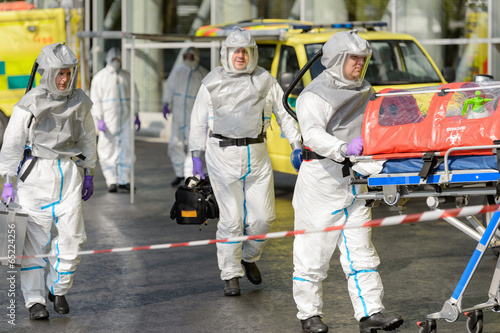 Biohazard team with stretcher walking on street