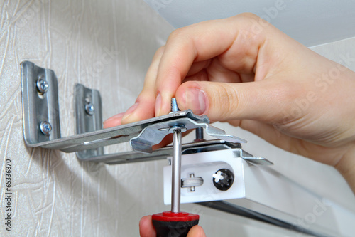 vertical blinds mounting brackets, hand with a screw close up