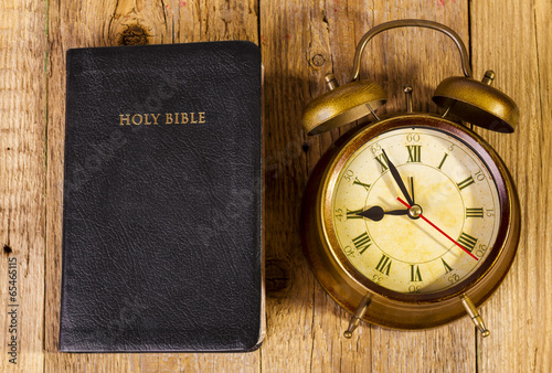 Bible with clock on wood