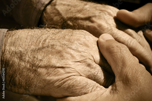 young man holding the hands of an old man