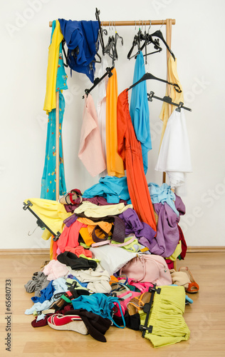 Untidy cluttered woman wardrobe with clothes on the floor.