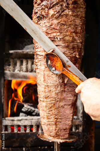 Doner meat being sliced from rotating spit