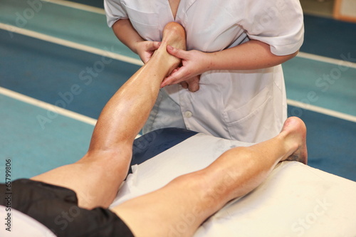 masseuse massaging athlete' s Achilles tendon after running