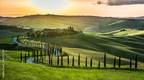 Sunset over the winding road with cypresses in Tuscany