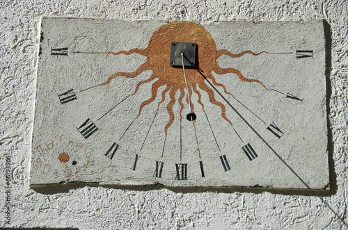 Ancient sundial with signs of the zodiac on white wall