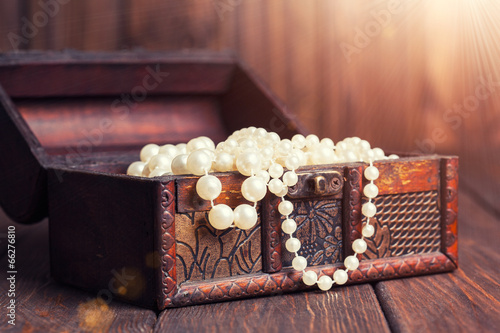 old treasure chest with pearl necklaces standing on wooden table