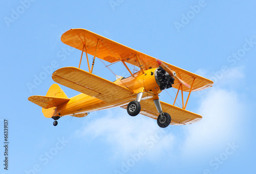 Yellow biplane on the blue sky.