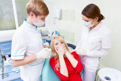 Female patient in dentist office afraid of doctor, procedure