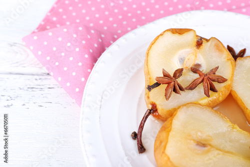 Baked pears with syrup on plate, on color wooden background