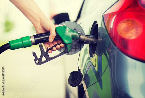 man pumping gasoline fuel in car at gas station