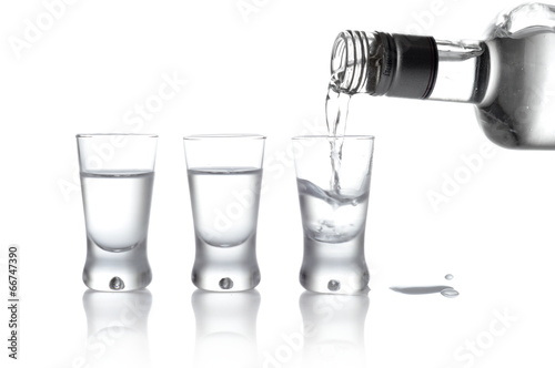 Bottle and glasses of vodka poured into a glass isolated on whit