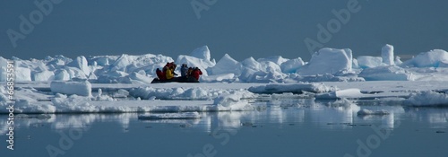 People in inflatable taking pictures of icebergs