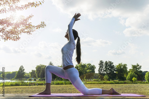 Pretty woman doing yoga exercises in the park.