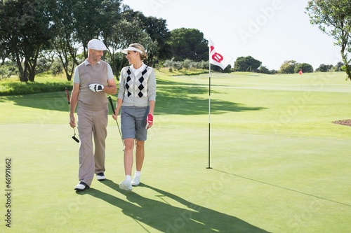 Golfing couple smiling at each other on the putting green
