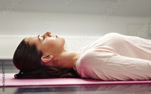 Woman lying on yoga mat relaxing her muscles