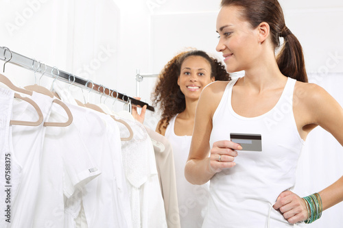 Kobiety w sklepie odzieżowym płaca za zakupy karta kredytową.