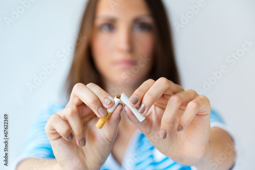 Young woman refuses to smoke and breaks cigarette.